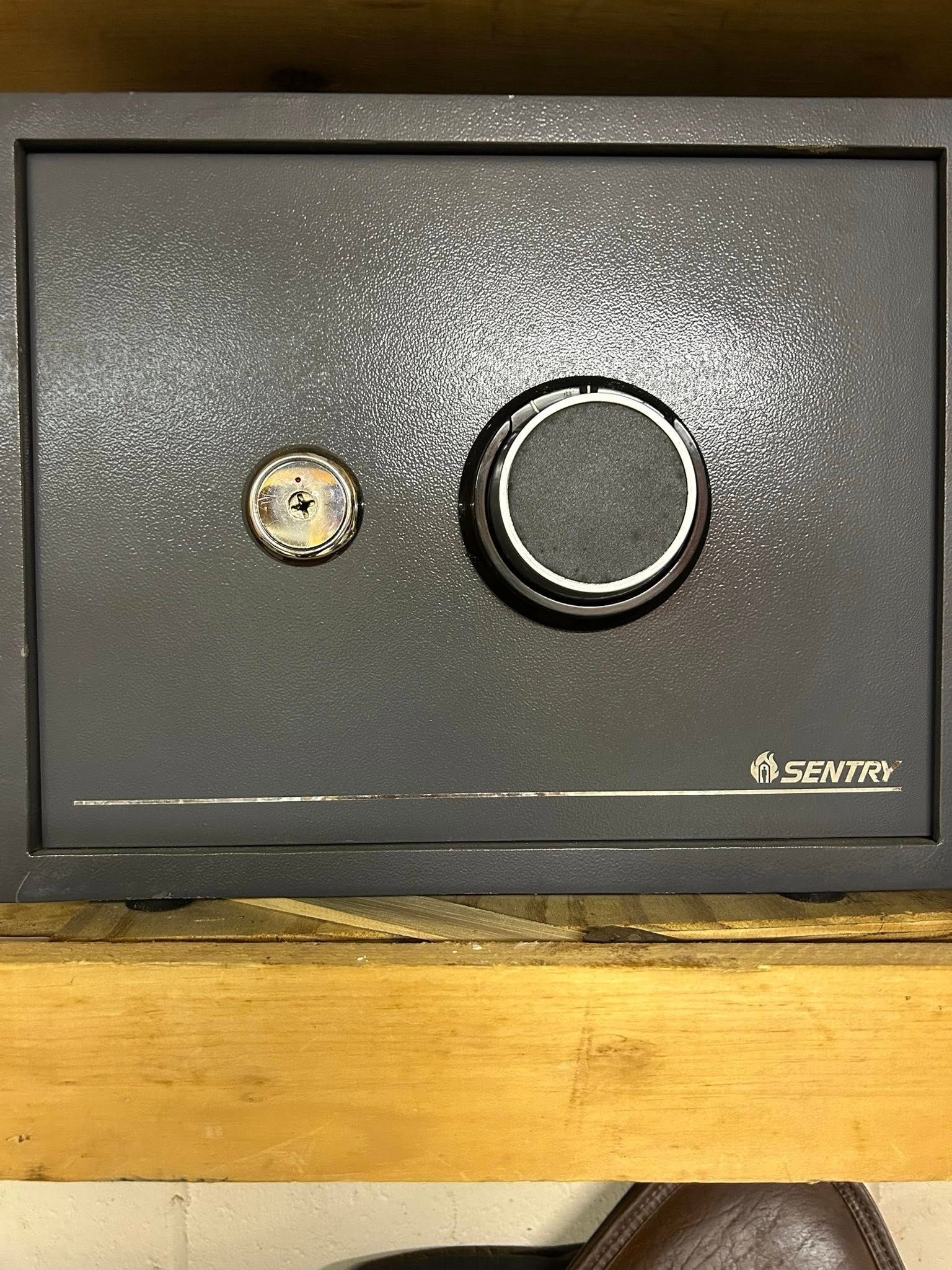 A dark gray Sentry safe with a combination dial and key lock.