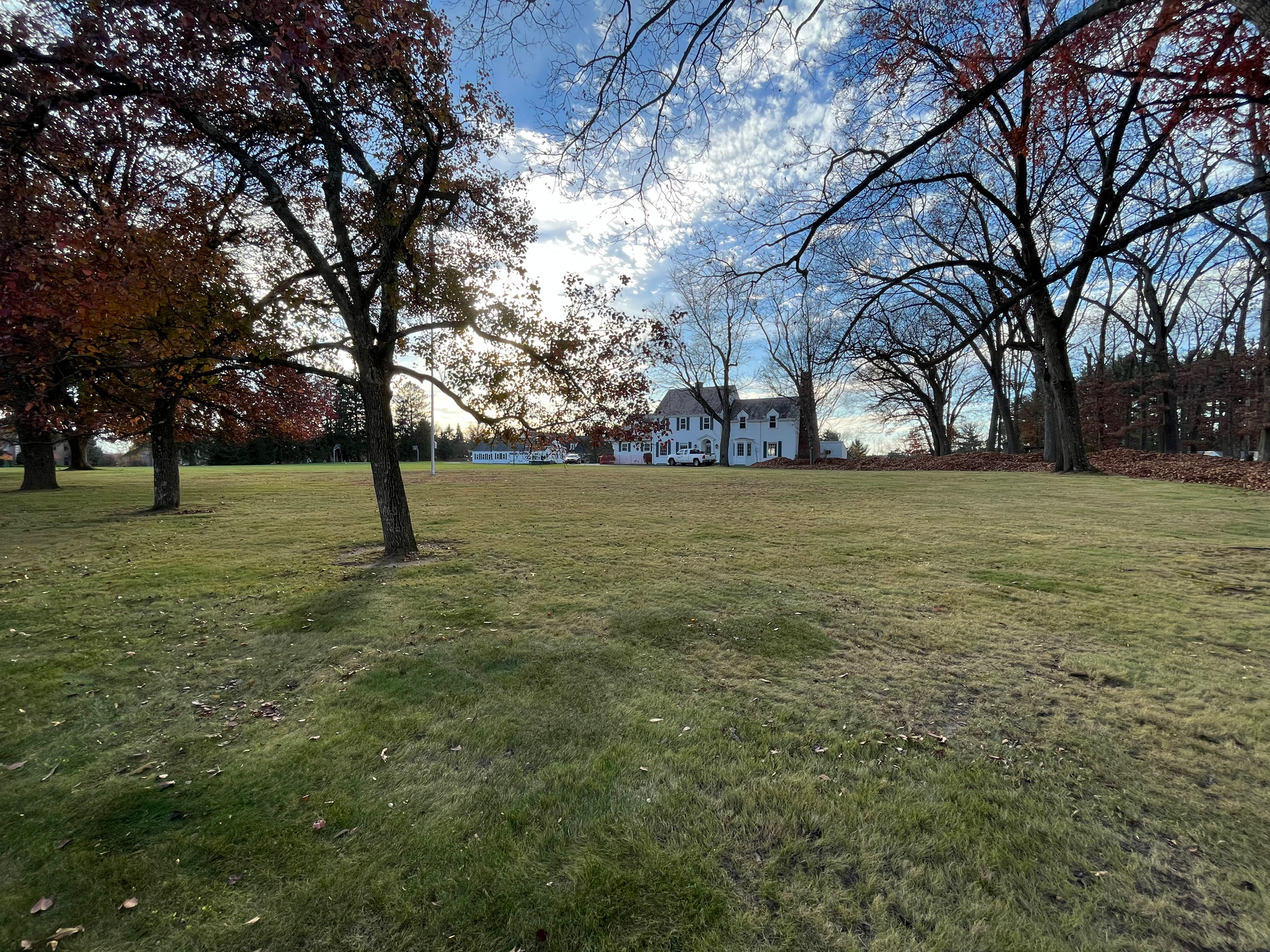 a large grassy field with trees and a house in the background .