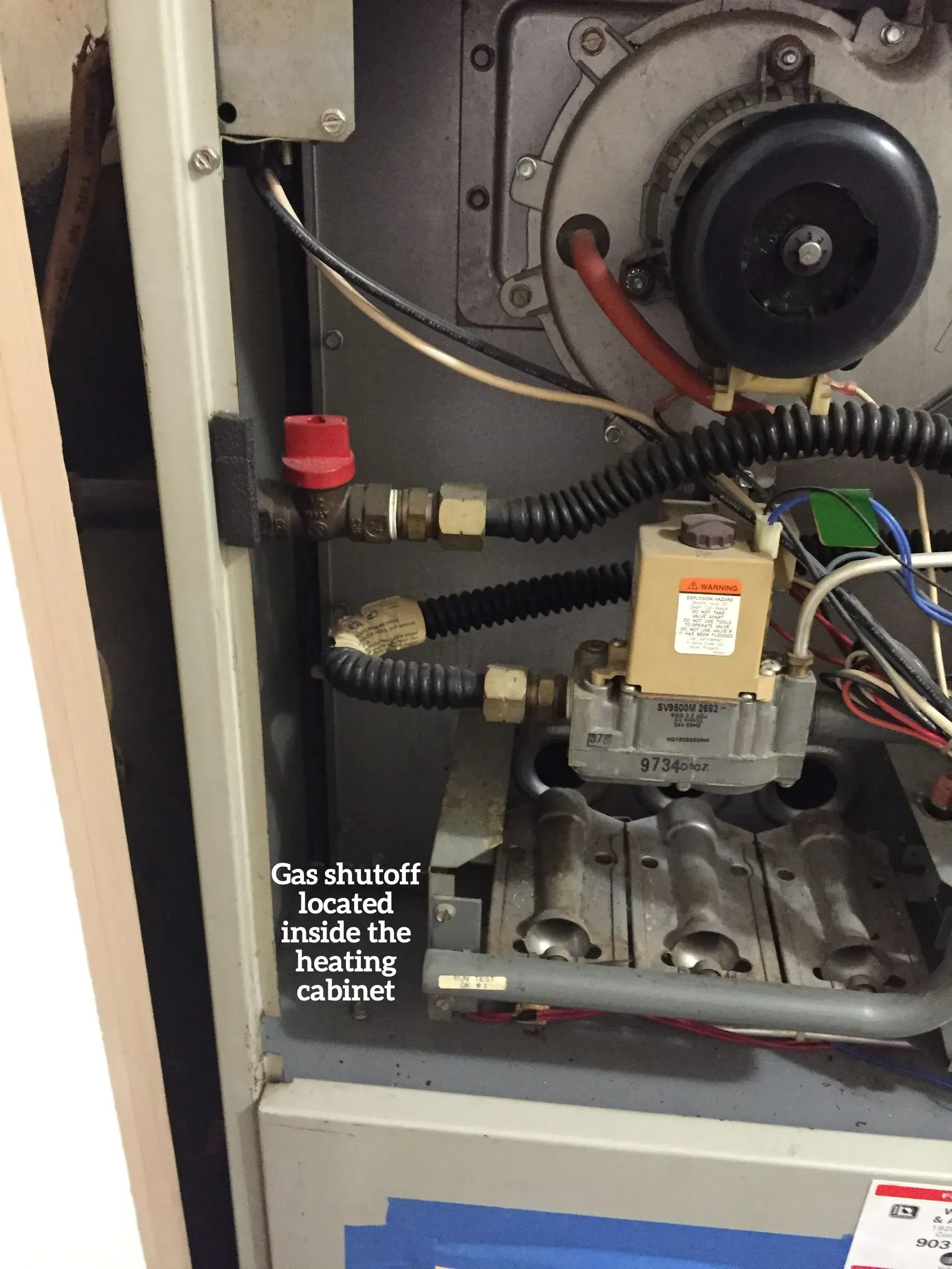 Interior view of a gas furnace with a red-handled gas shut-off valve labeled in the upper left corner.