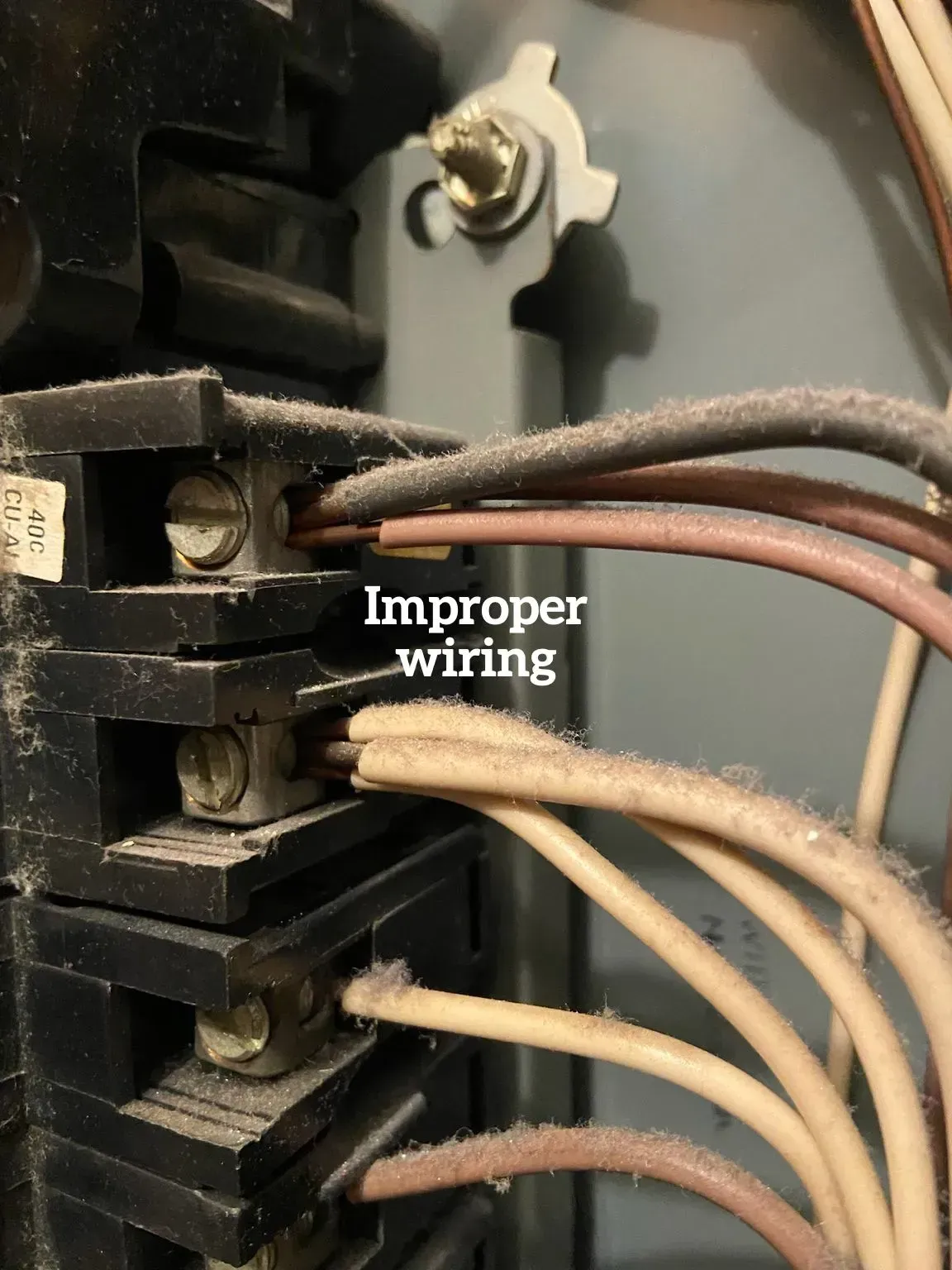 Close-up of an electrical panel showing multiple wires improperly connected to single terminals with a text overlay.