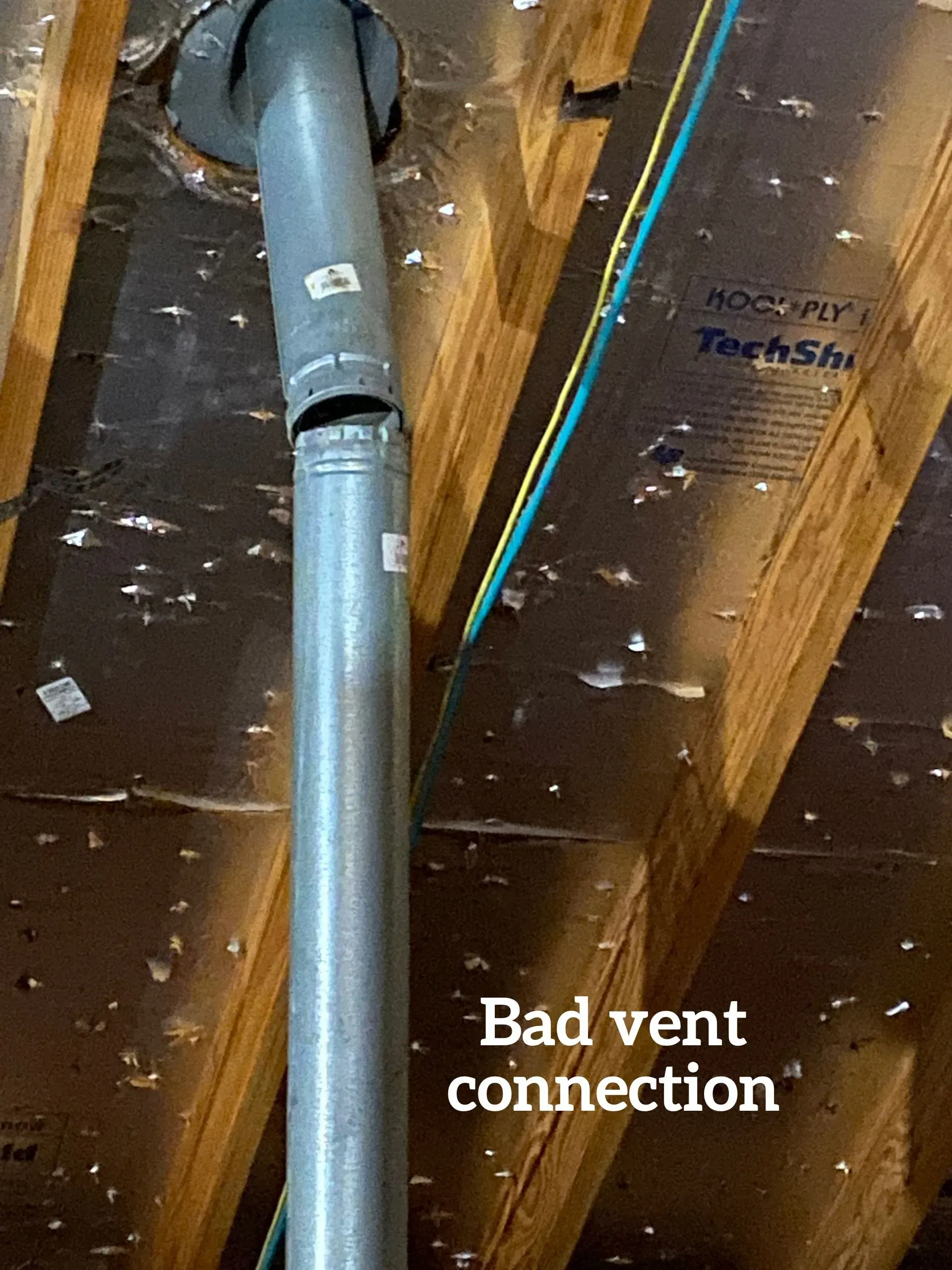 A metal vent pipe in an attic is disconnected at a joint, leaving a gap. The text 