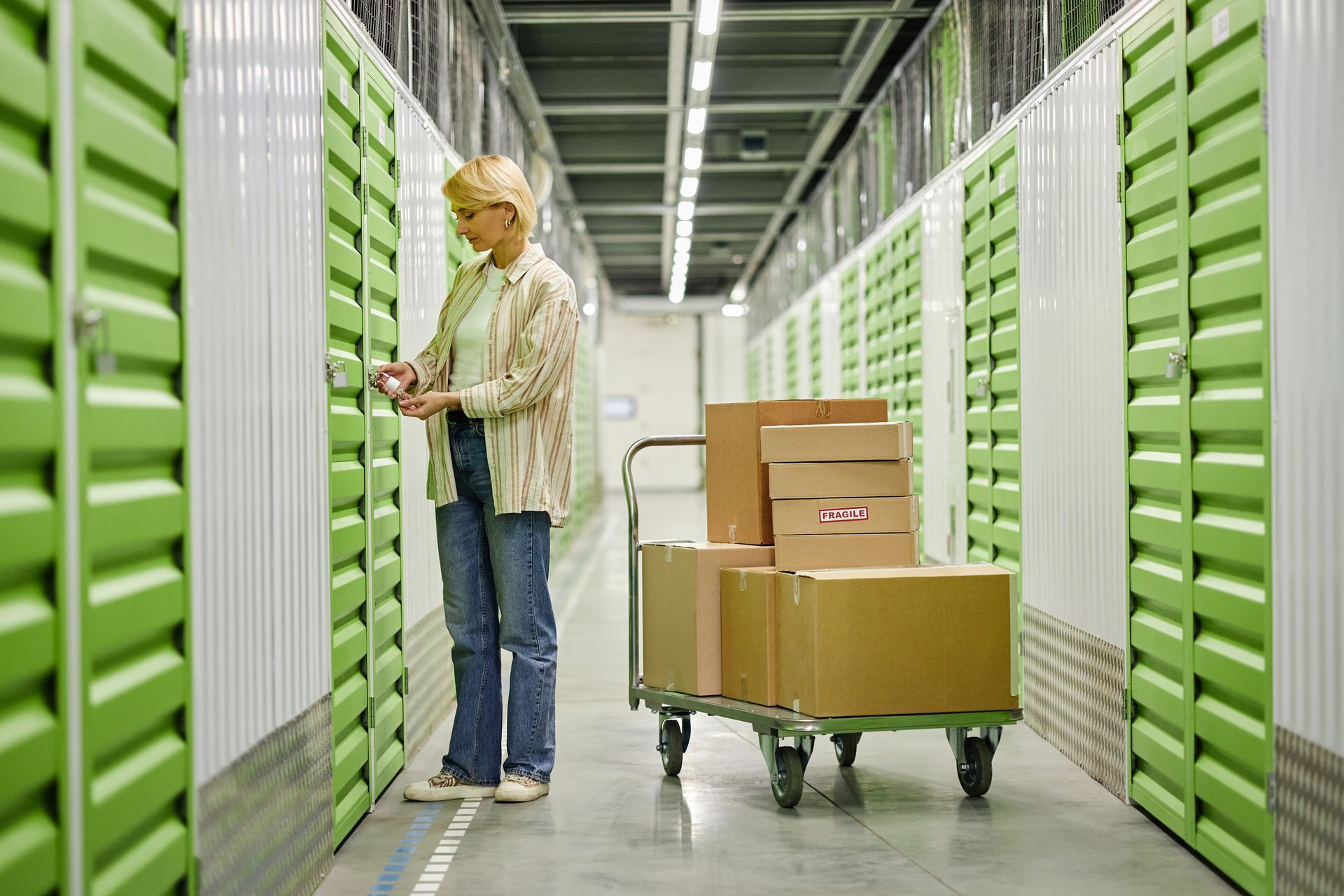 Woman unlocking storage unit while moving cardboard boxes. Woman unlocking storage unit while moving cardboard boxes.