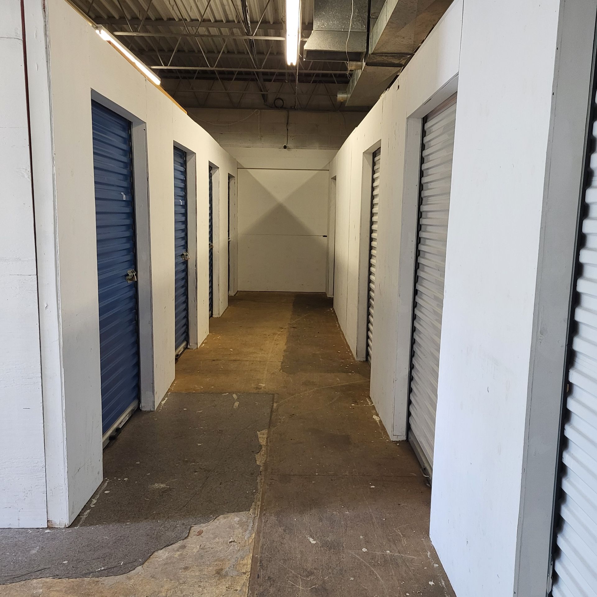 A small storage unit with red doors and a mattress wrapped in plastic.