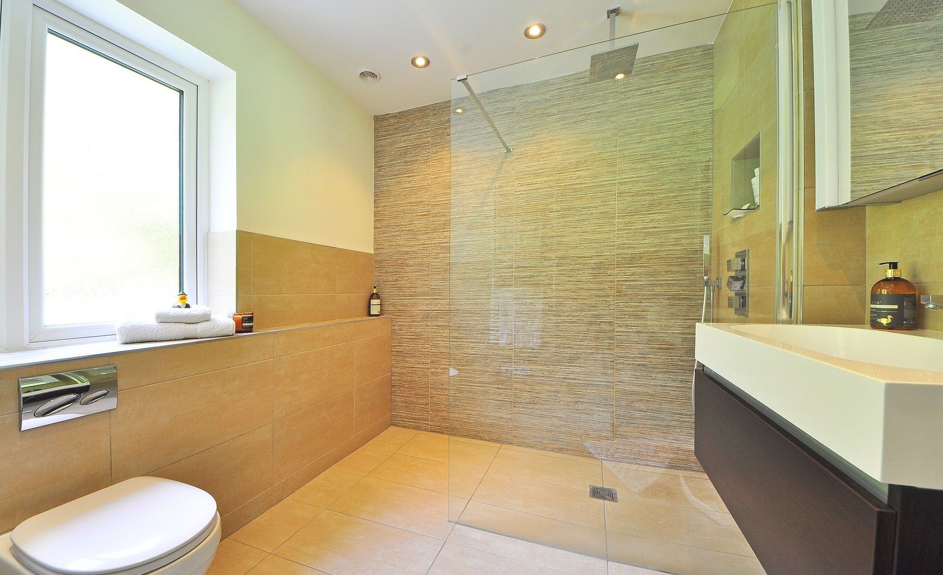 Patio vitré avec table, chaises, plantes et vue sur un bassin. Sol gris et murs blancs.