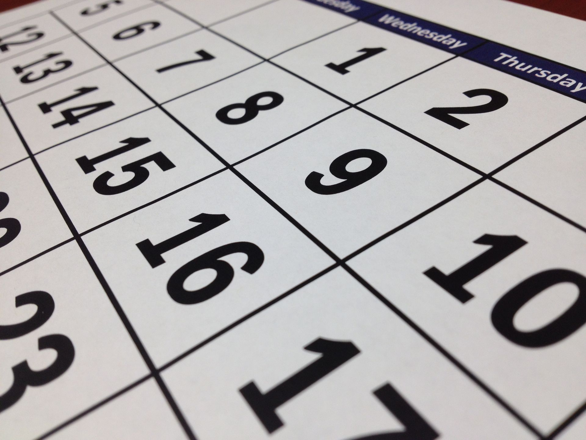 Close-up of a tilted monthly calendar with bold black dates on white pages.