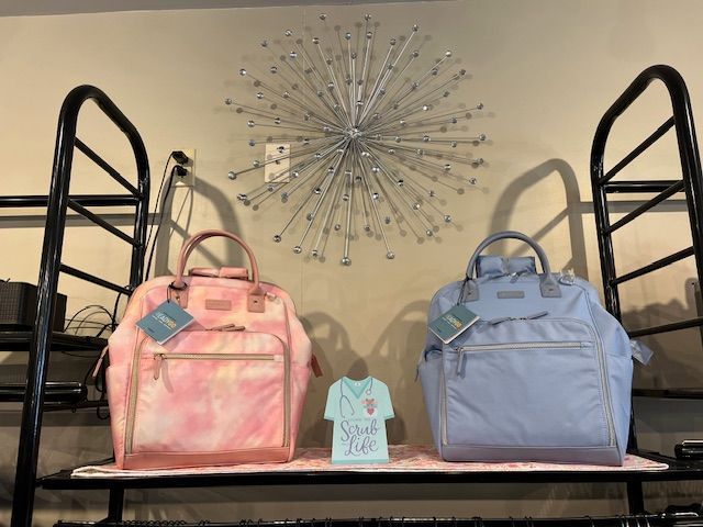 Two backpacks are sitting on a shelf in front of a wall clock.
