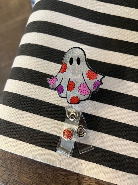 A badge reel with a ghost on it is sitting on a striped cloth.