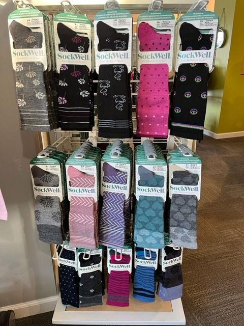 A variety of socks are displayed on a rack in a store.