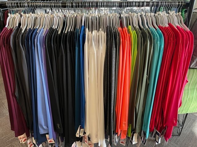 A bunch of clothes are hanging on a rack in a store.
