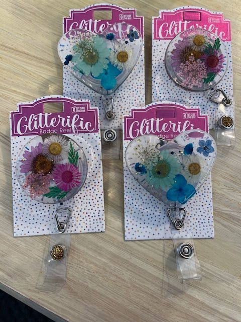 Four badge reels with flowers on them are sitting on a table.