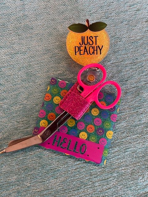 A pair of scissors next to a sticker that says just peachy