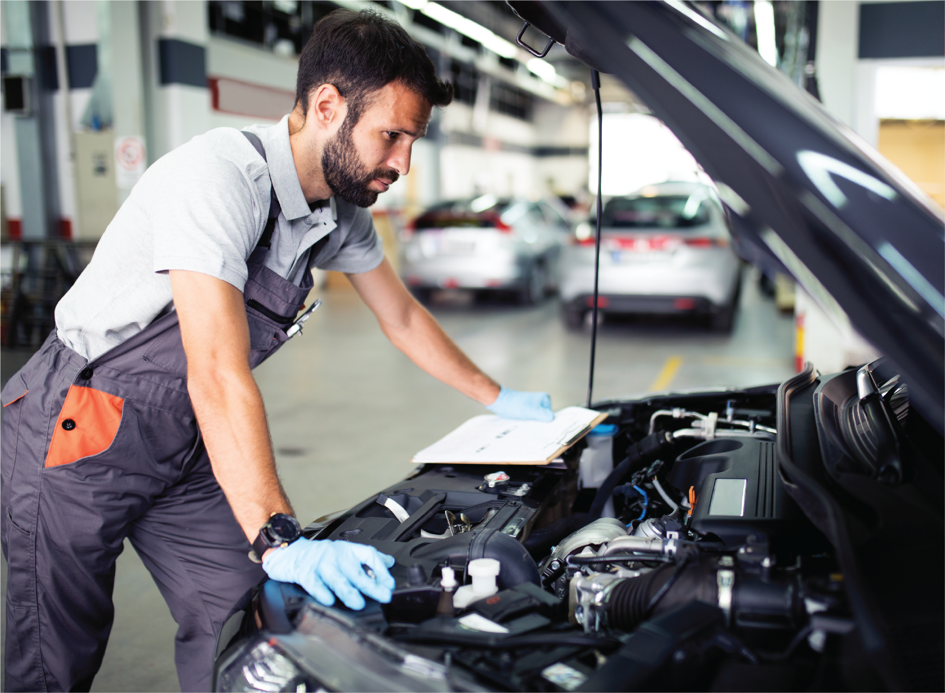 A man is working on the engine of a car in a garage.