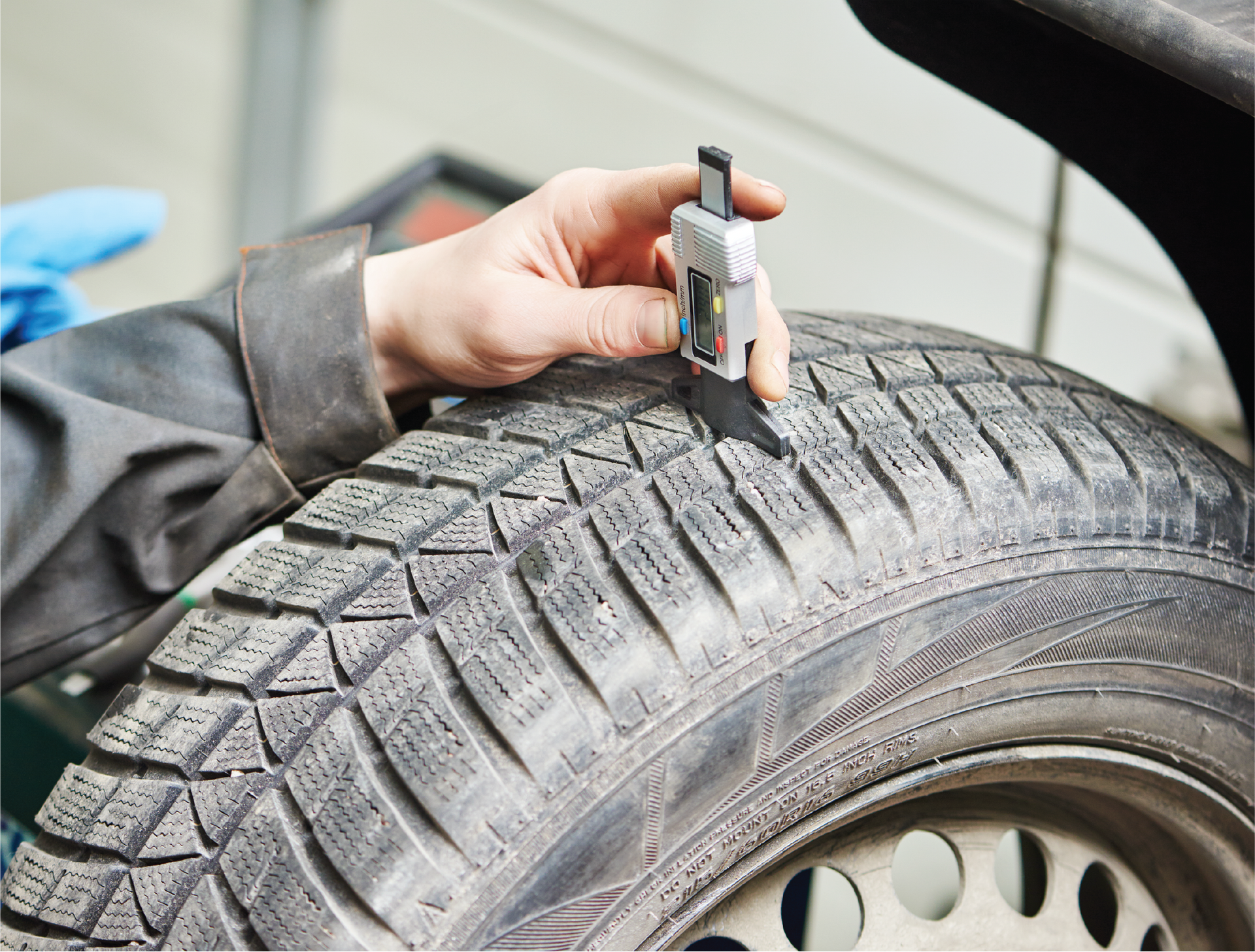 A person is measuring the depth of a tire with a device.