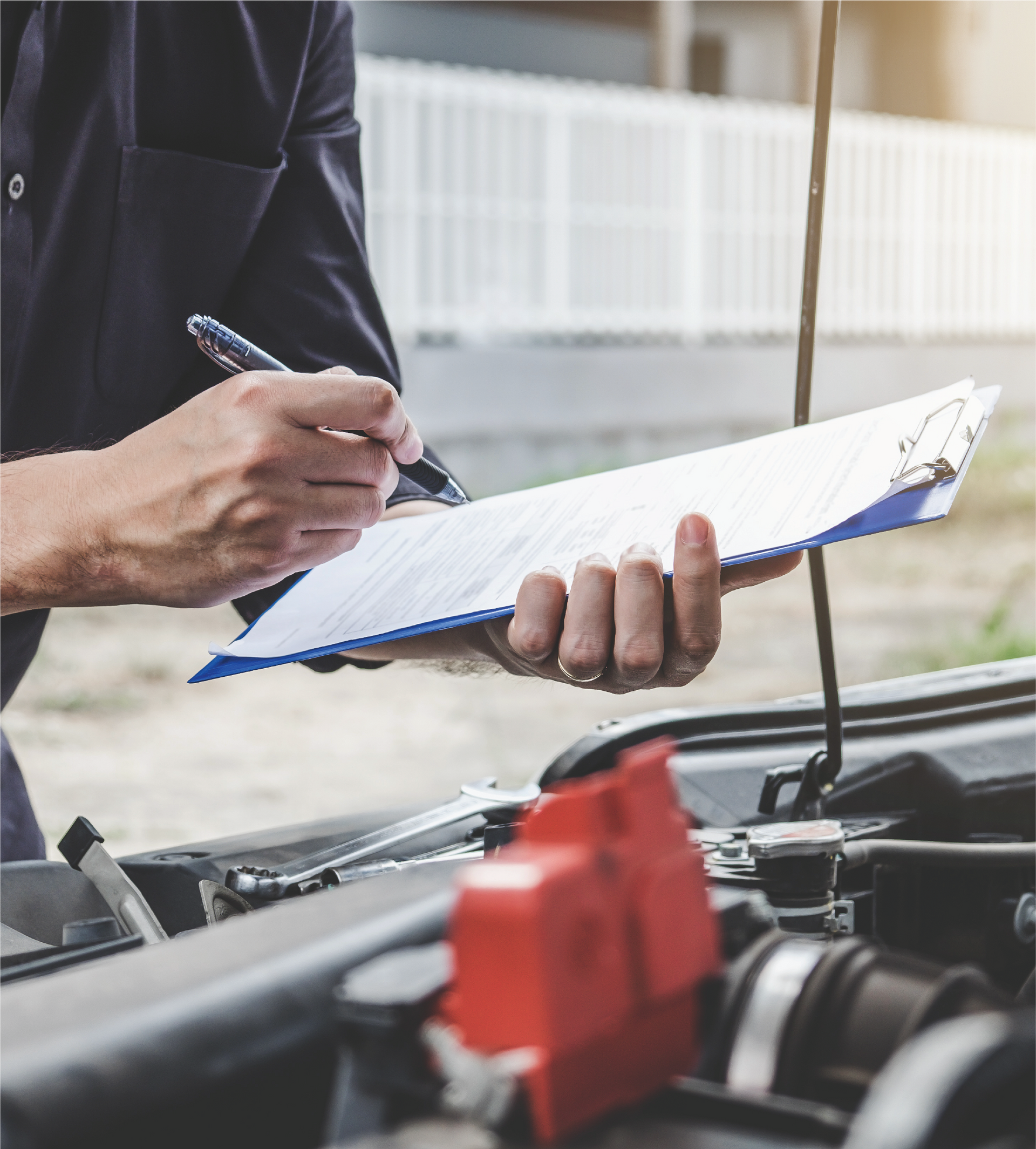 A man is writing on a clipboard while standing next to a car.