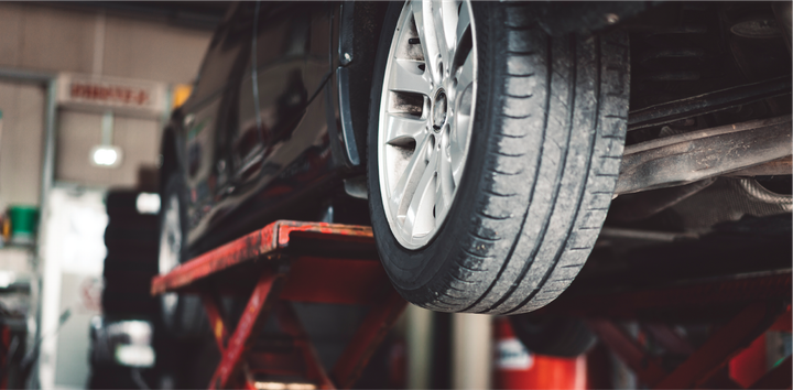 A car is sitting on a lift in a garage.