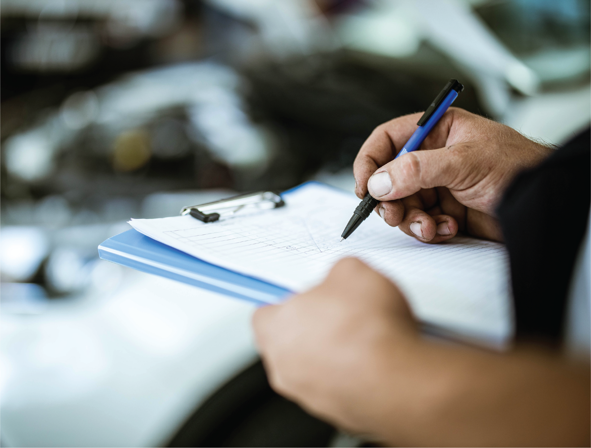 A person is writing on a clipboard with a pen.