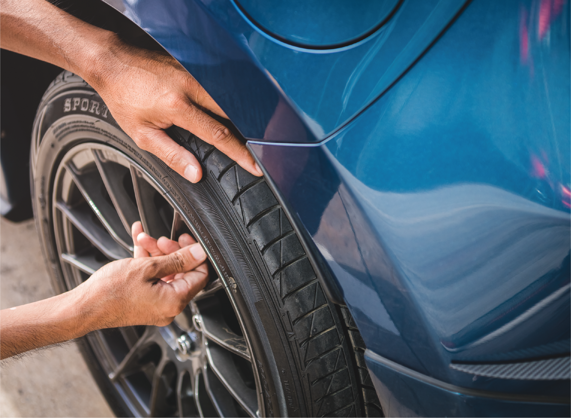 A person is putting a tire on a blue car.