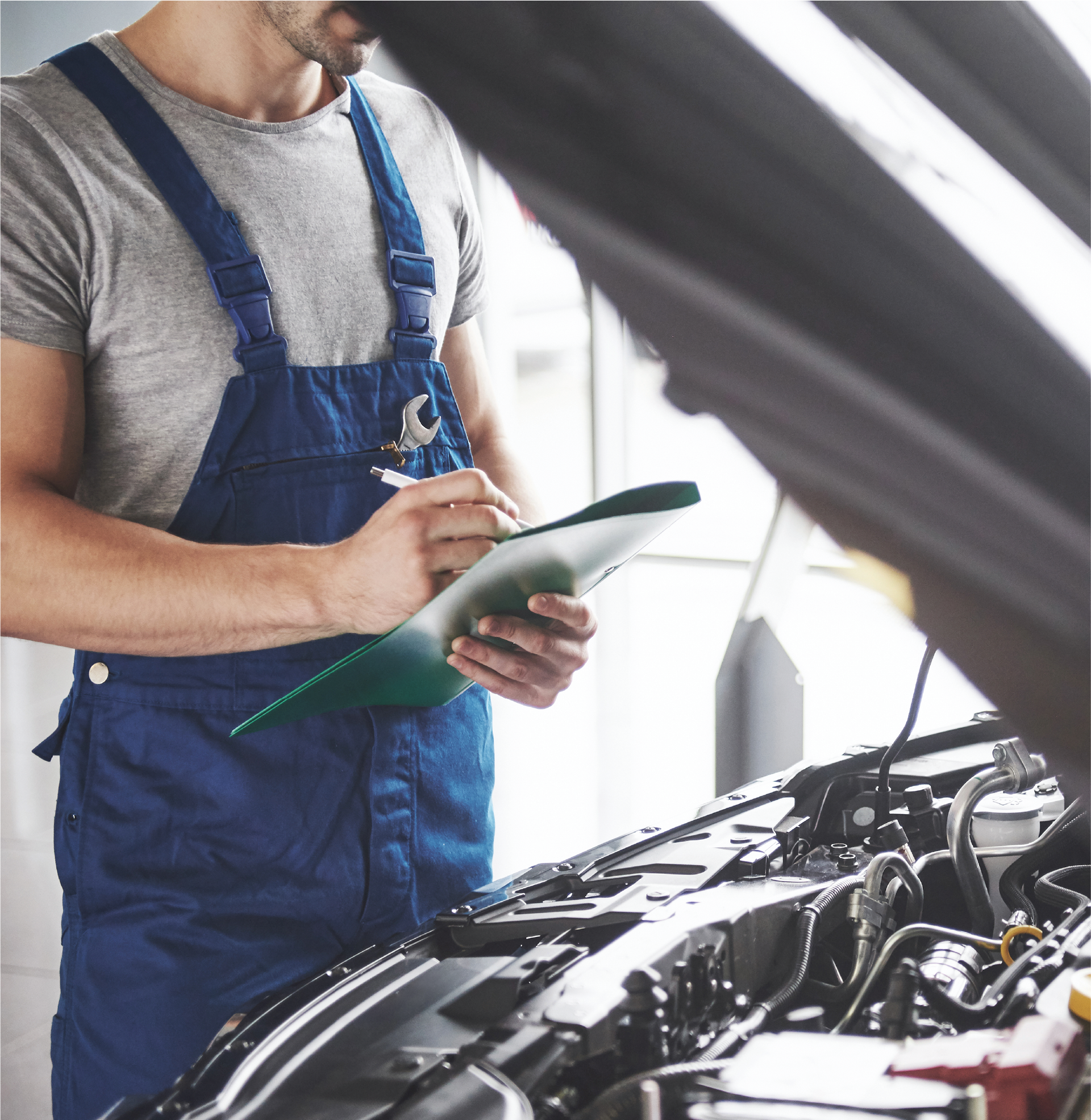 A man in blue overalls is working on a car