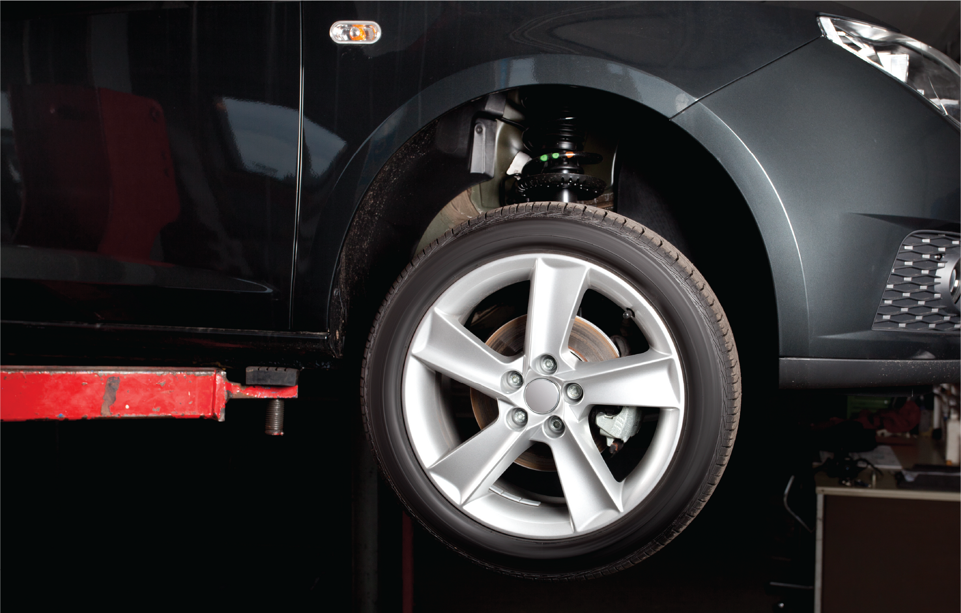 A black car is sitting on a lift in a garage.