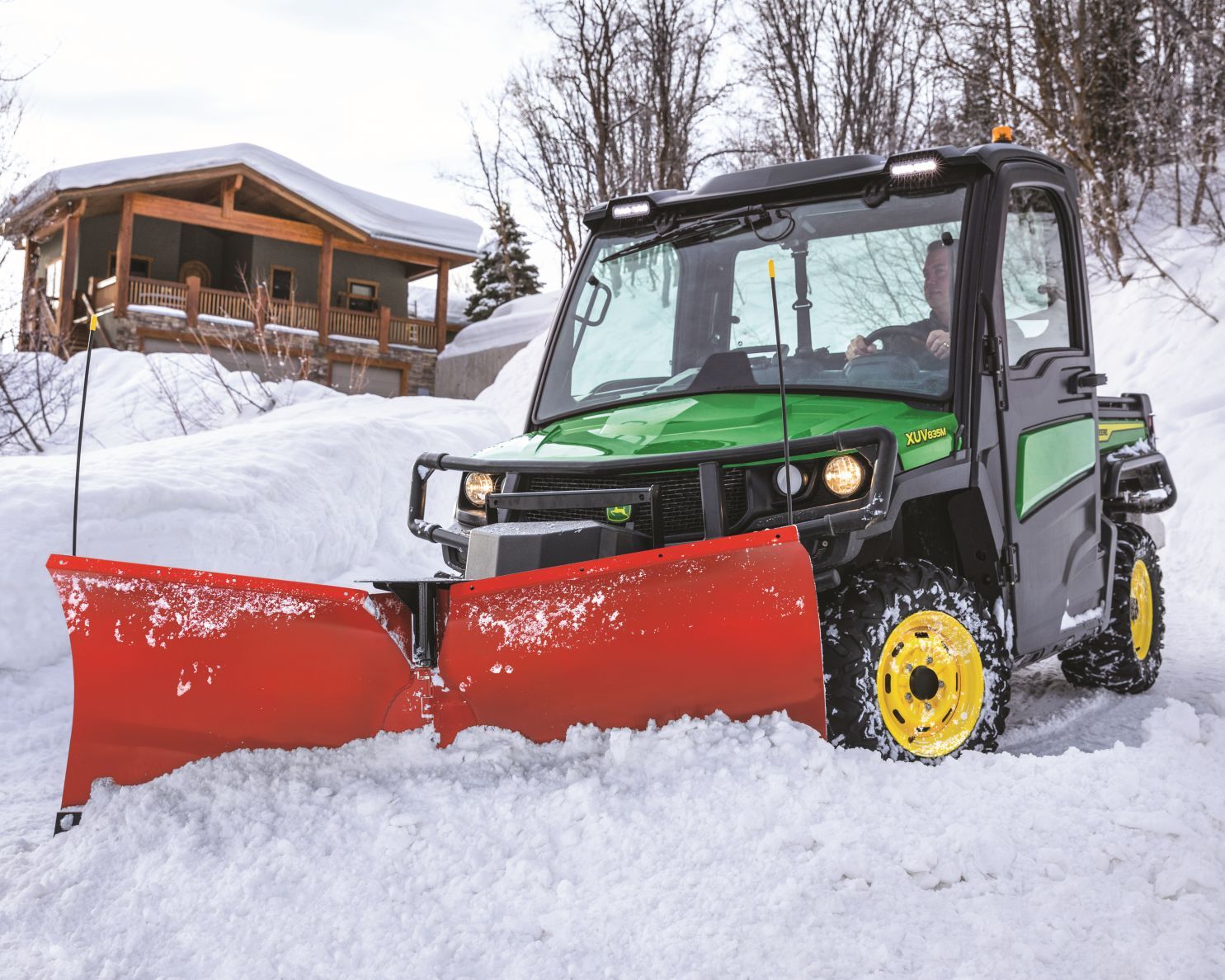 red snowblade on a John Deere Gator pushes snow