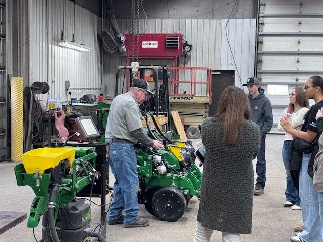 A group of high school students learns about planter row units