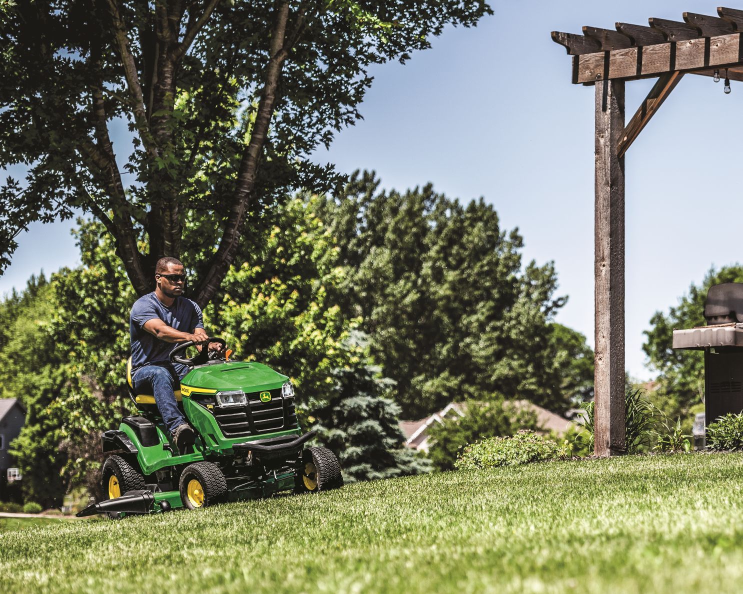man mows the lawn with a John Deere S240 riding mower