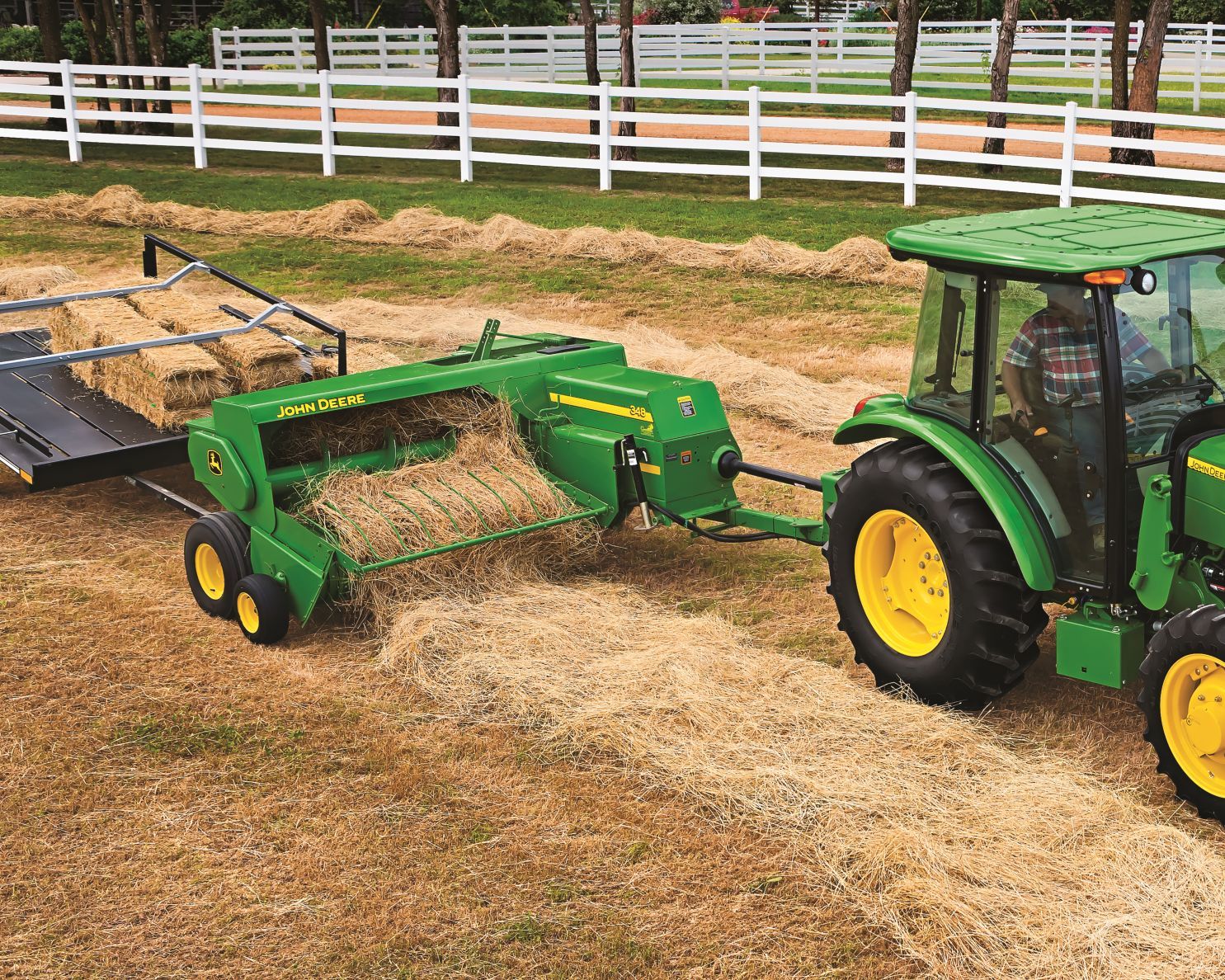 John Deere tractor pulls a 348 small hay baler through a field