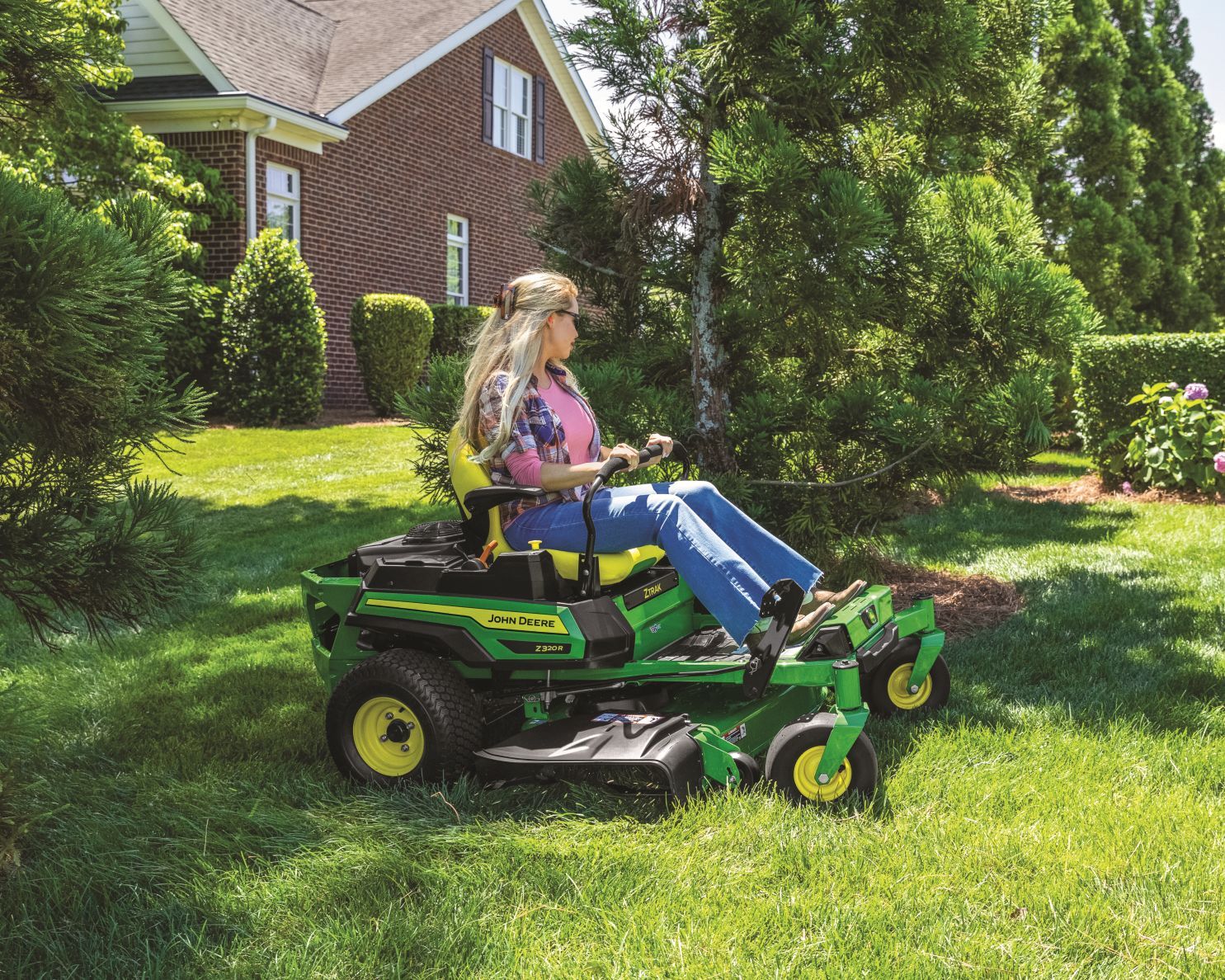 woman mows lawn with John Deere zero-turn mower