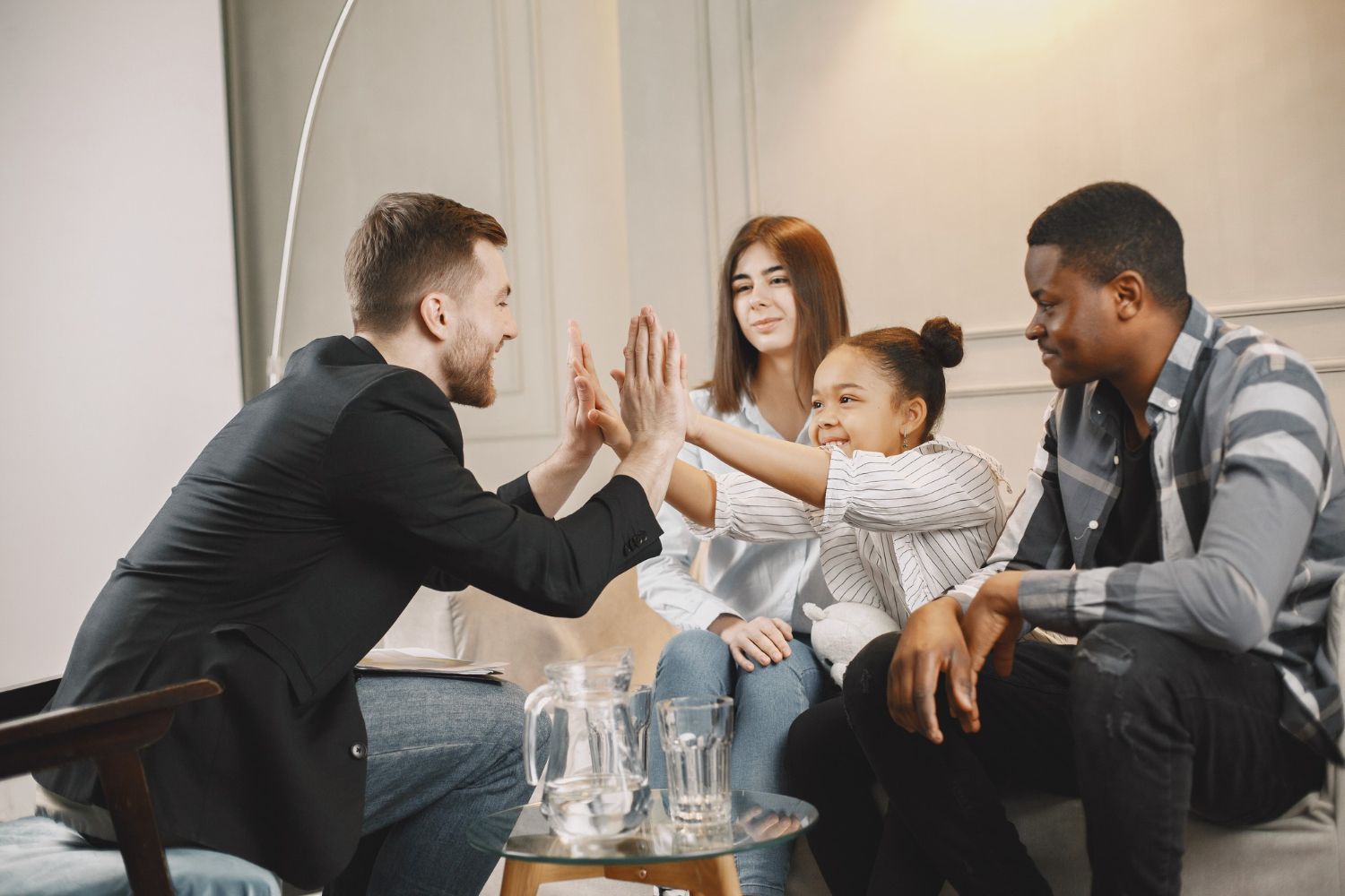 A family and a therapist give each other a high-five in a bright room.