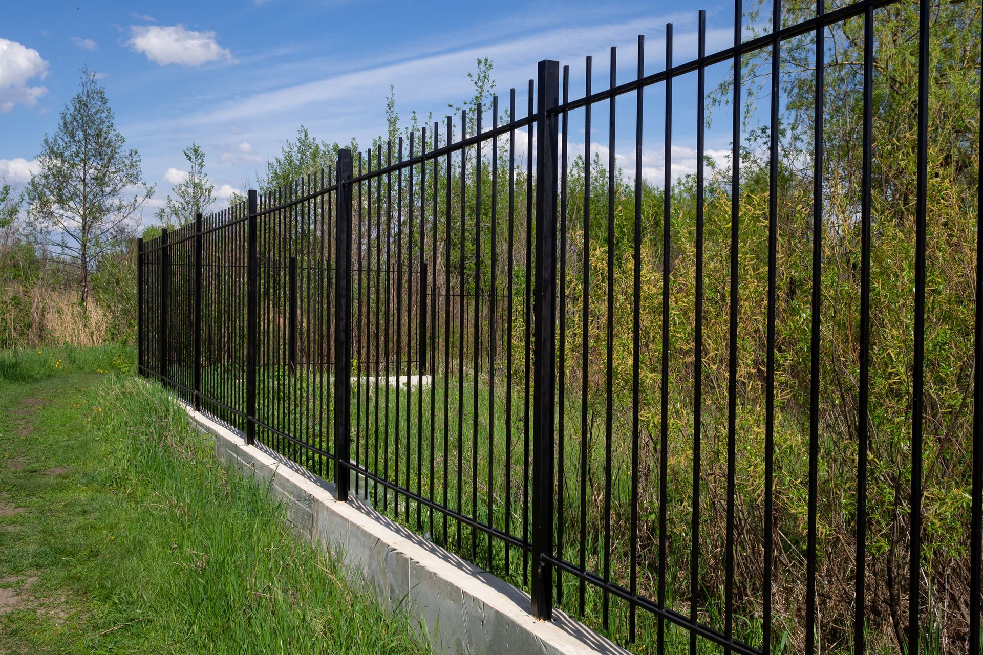 A black fence with a blue sky in the background