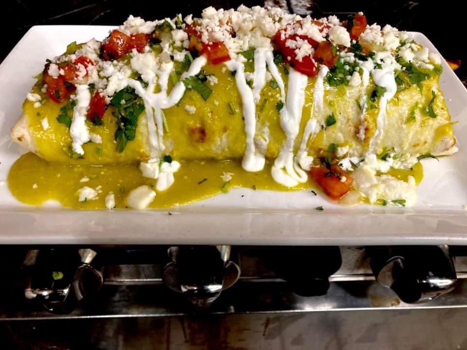 A burrito with sauce and cheese on a white plate