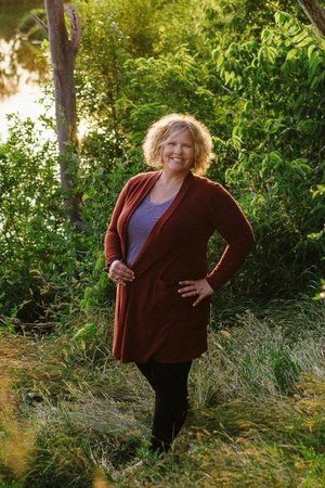 A woman in a red cardigan is standing in a field.