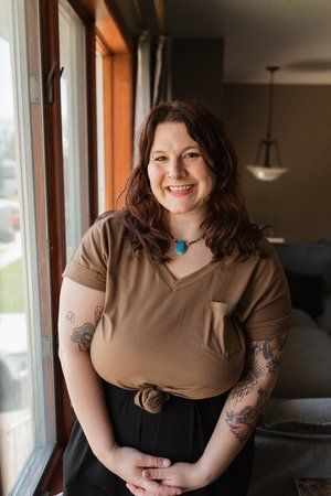 A woman is standing in front of a window smiling.