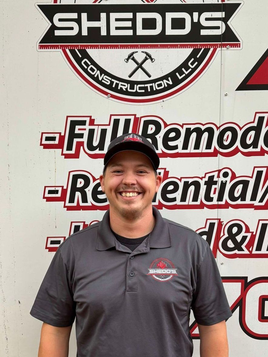 A man with a beard is wearing a white shirt and smiling