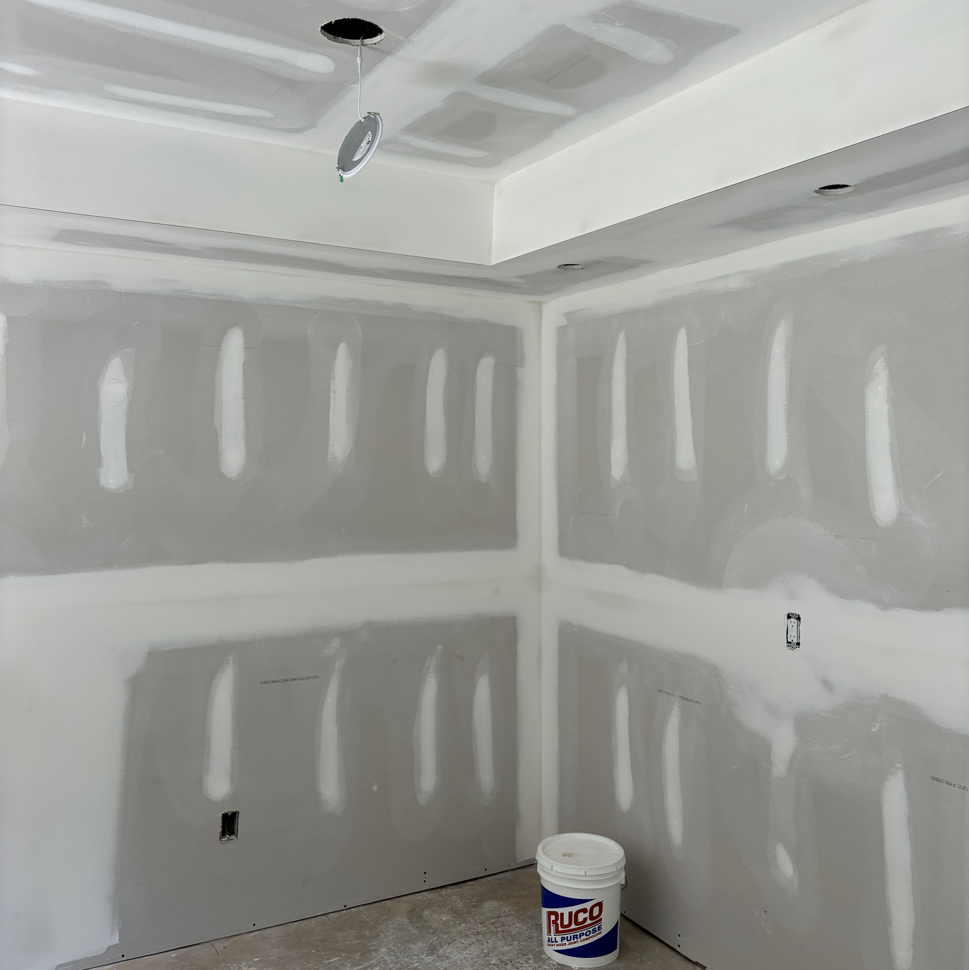 A room with drywall and a bucket of ag paint