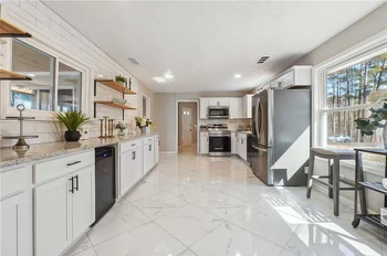 A kitchen with white cabinets , stainless steel appliances , and a large window.