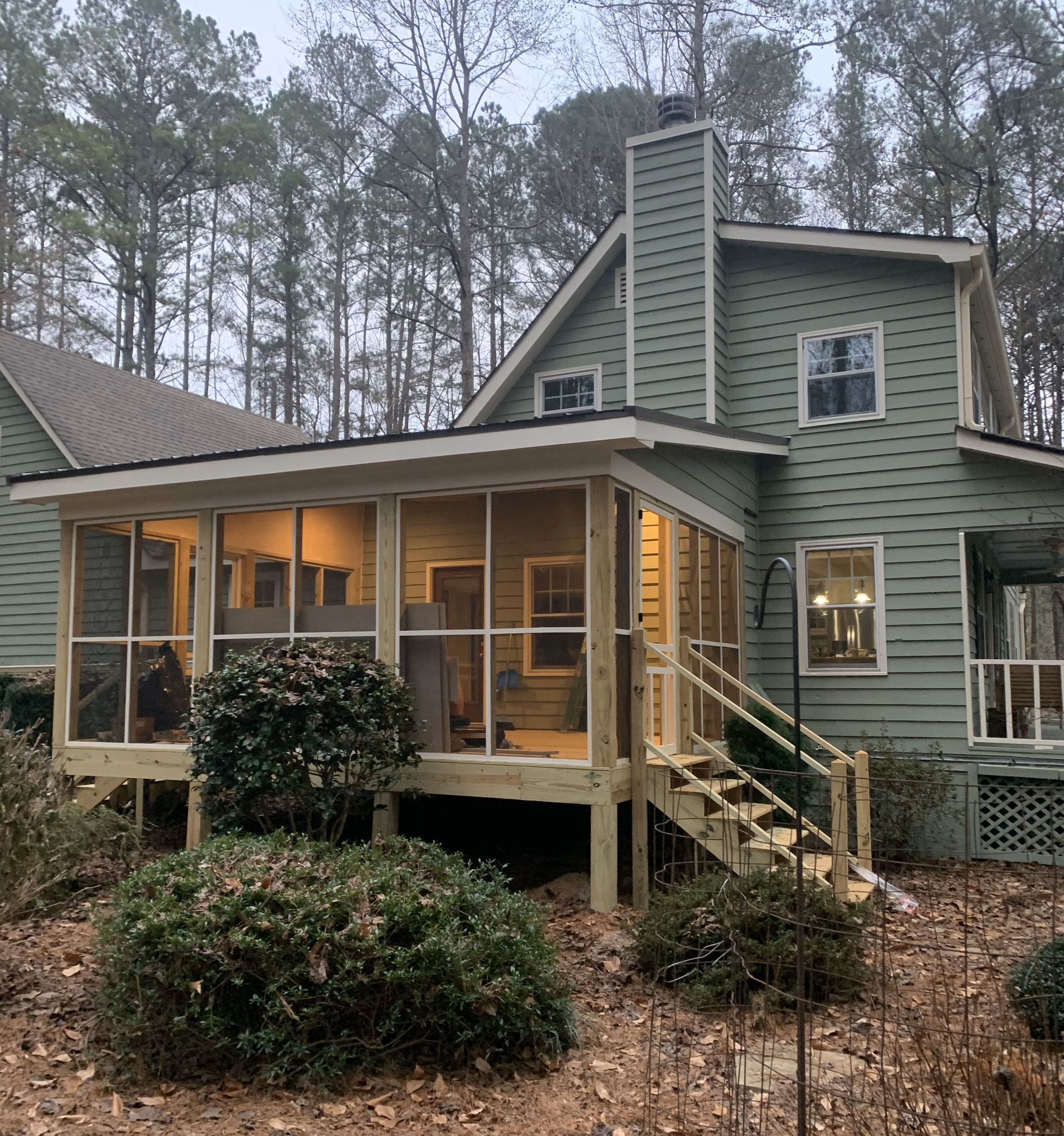 A green house with a screened in porch and stairs