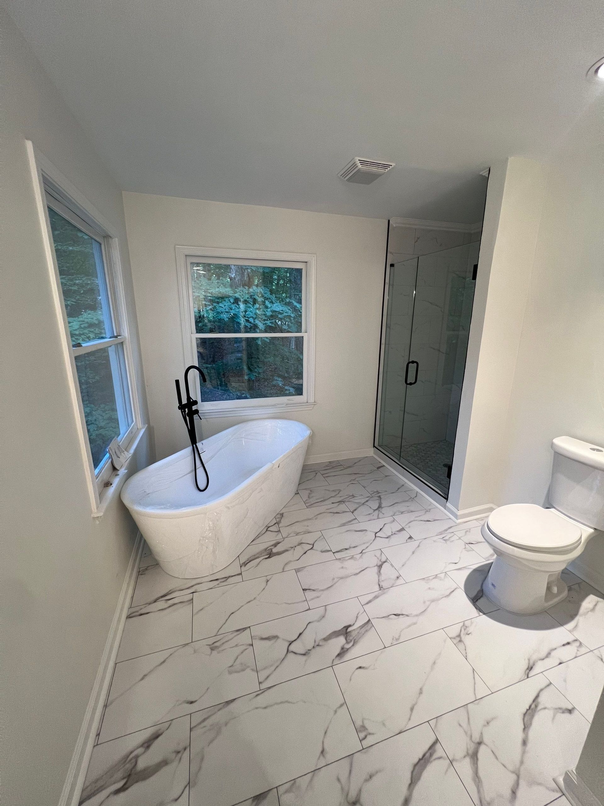 A bathroom with a tub , toilet , sink and shower.