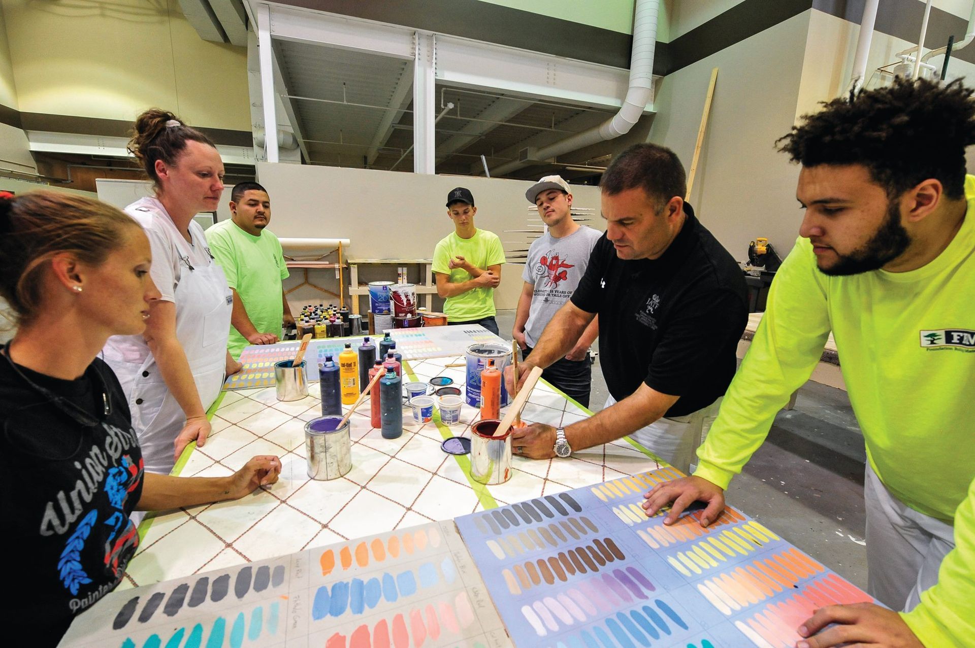 A group of NCIFTI apprentices gathered around a project table, analyzing color palettes and finishing materials.