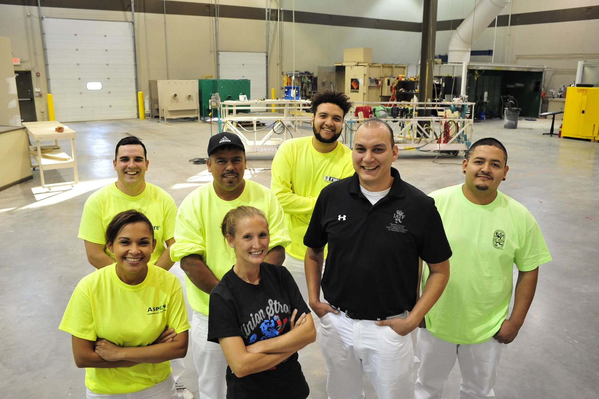 A group of NCIFTI painting apprentices posing together in the training warehouse.
