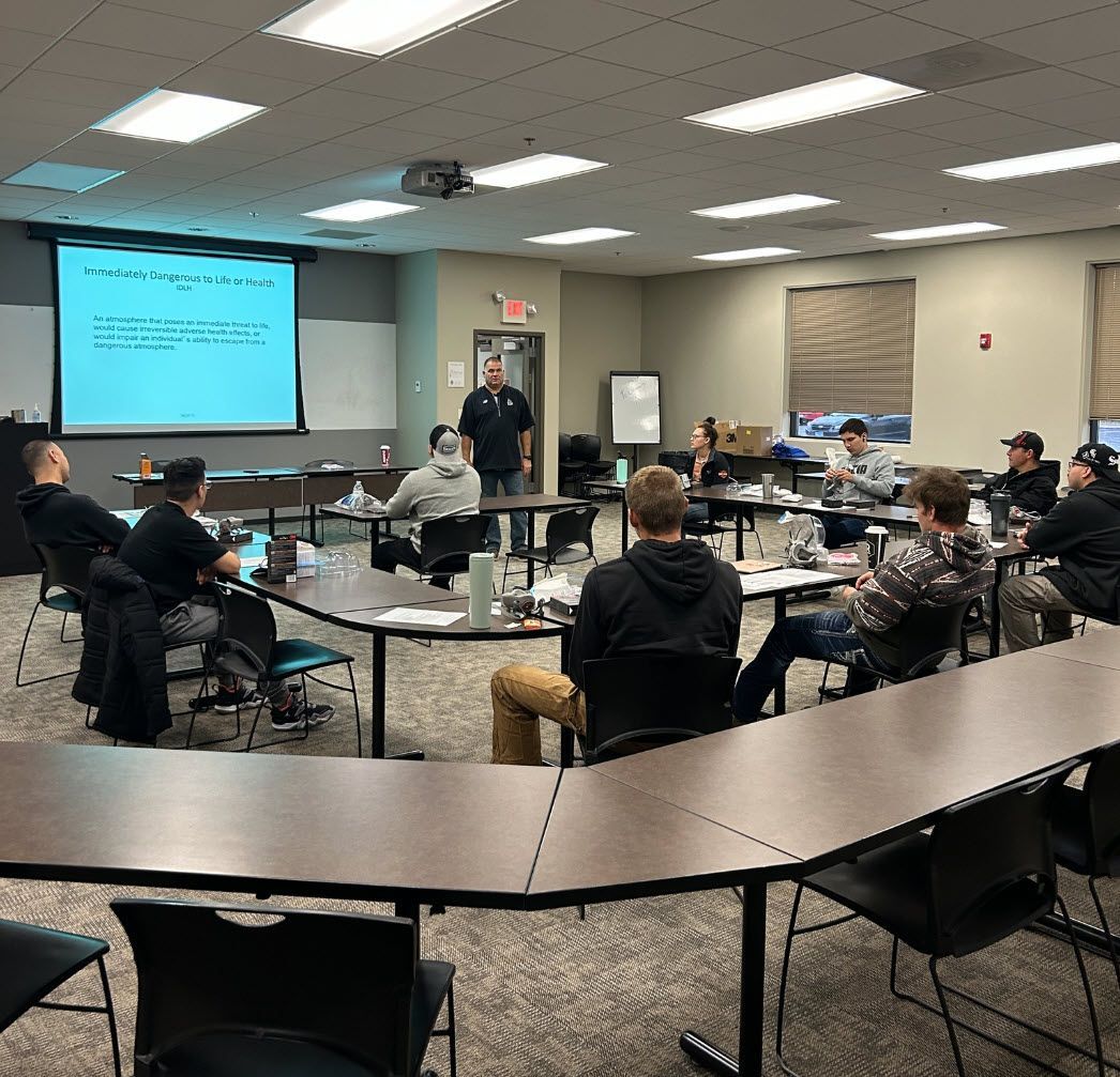 A group of jourmeypeople participating in a continued education seminar in a classroom.