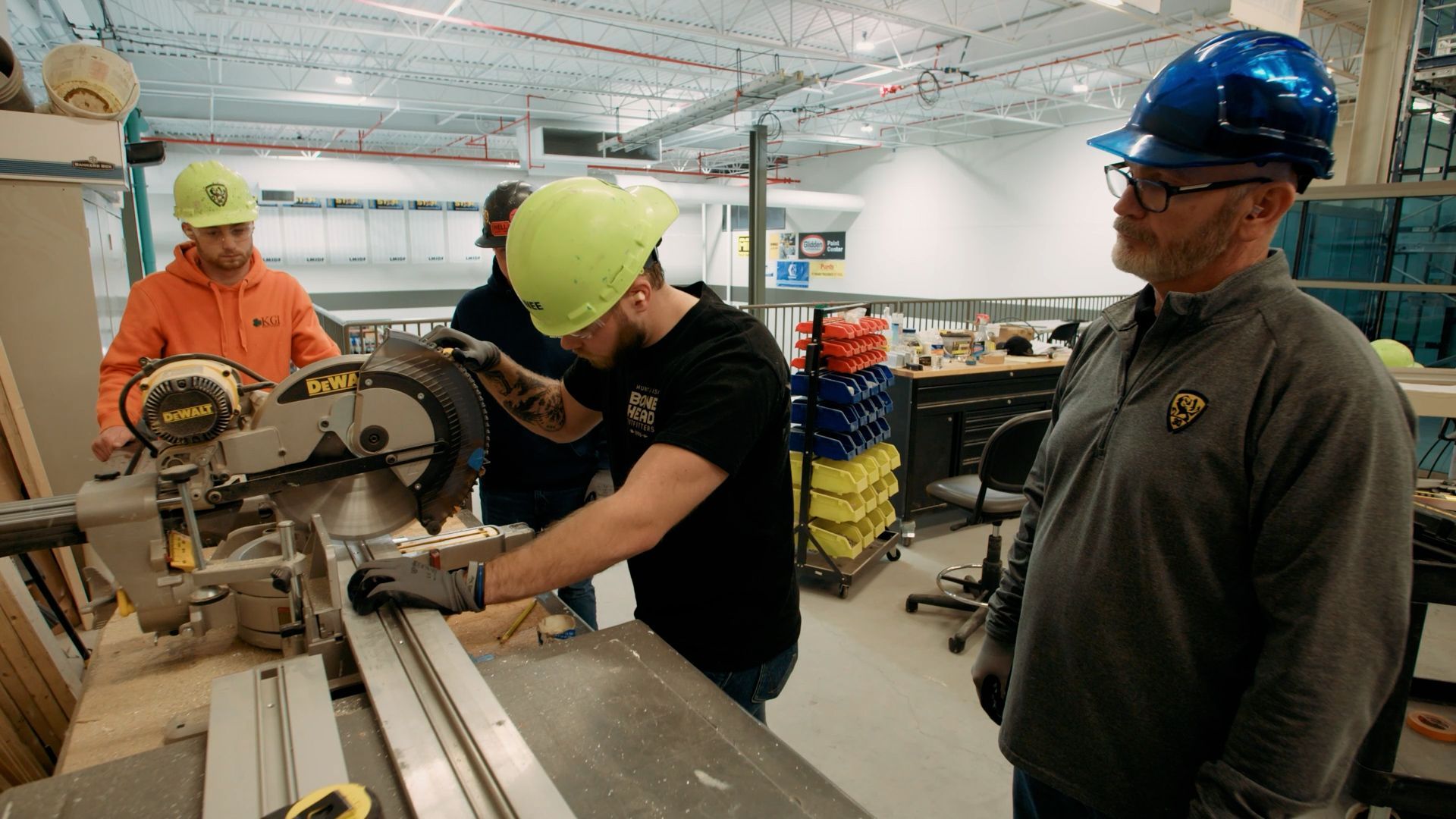 NCIFTI instructor supervising an apprentice using a professional miter sow to cut aluminum framing for glazing.