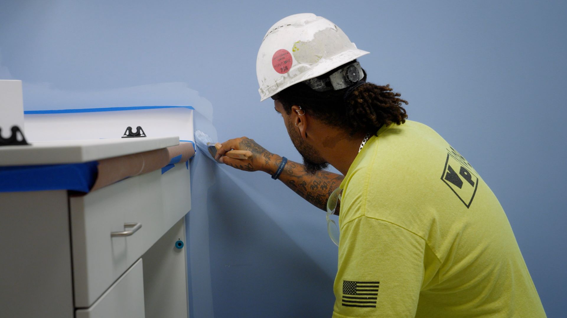 Close-up of a painter carefully applying paint to create a clean edge along a cabinet.