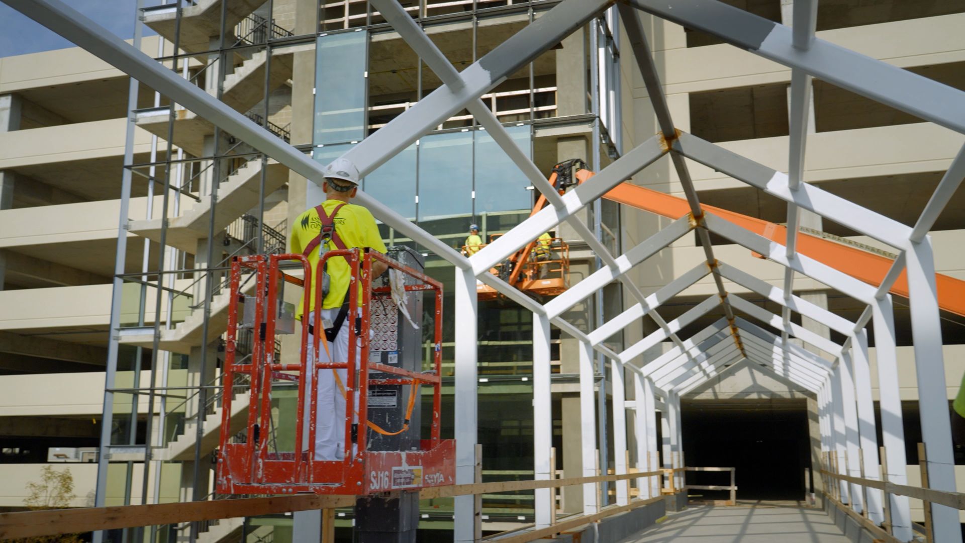 NCIFTI painters working from an orange lift to paint a large-scale industrial steel structure.