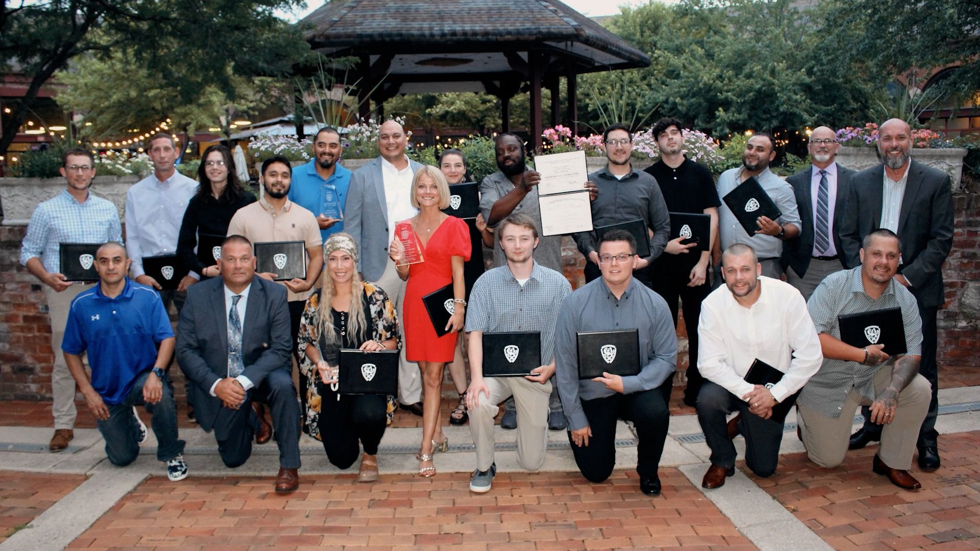 A group of NCIFTI graduates and instructors posing outdoors, with students holding their official completion certificates.