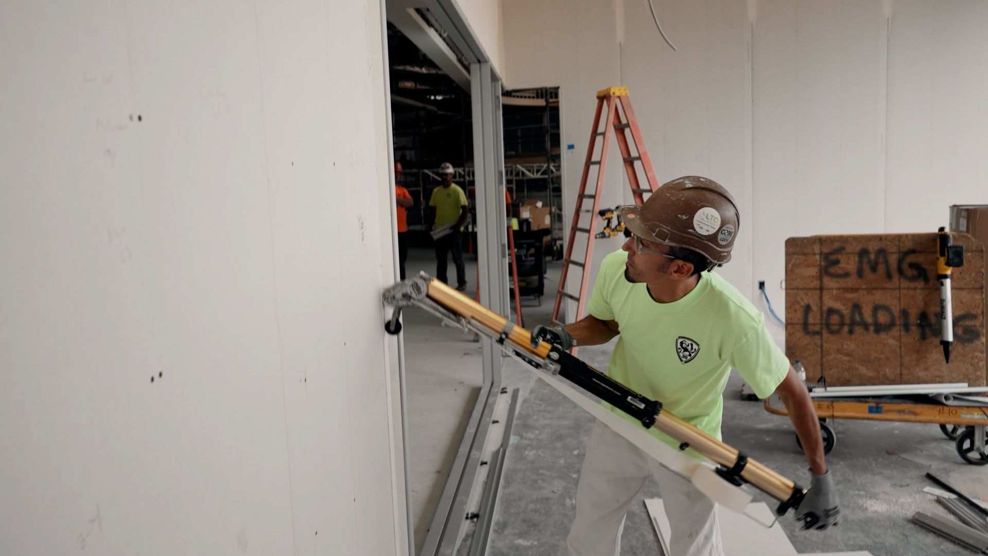 An NCIFTI student using an automatic drywall taper (bazooka) to efficiently apply tape and compound to a wall seam.