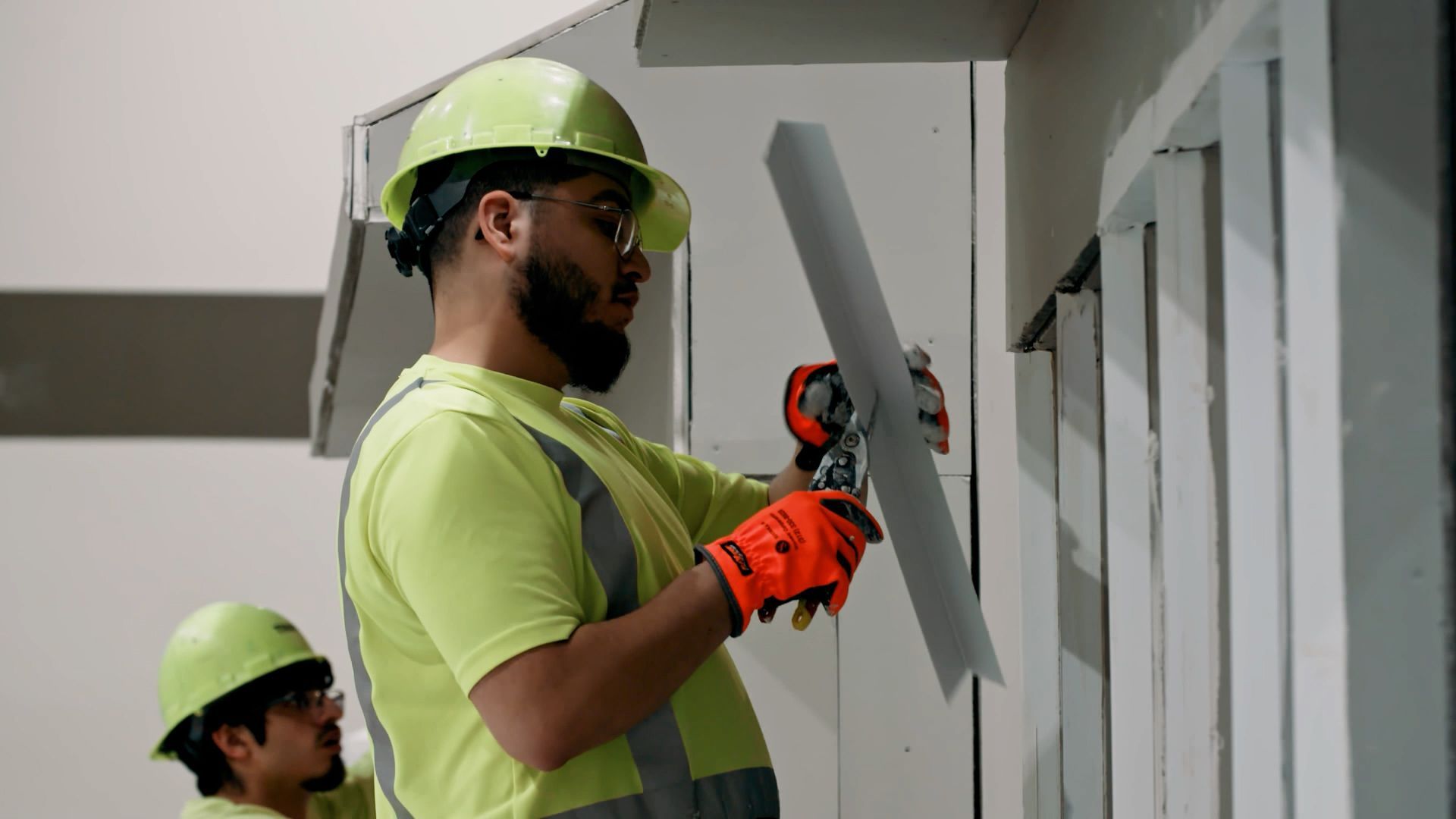 An NCIFTI apprentice using a broad knife to finish a drywall corner.