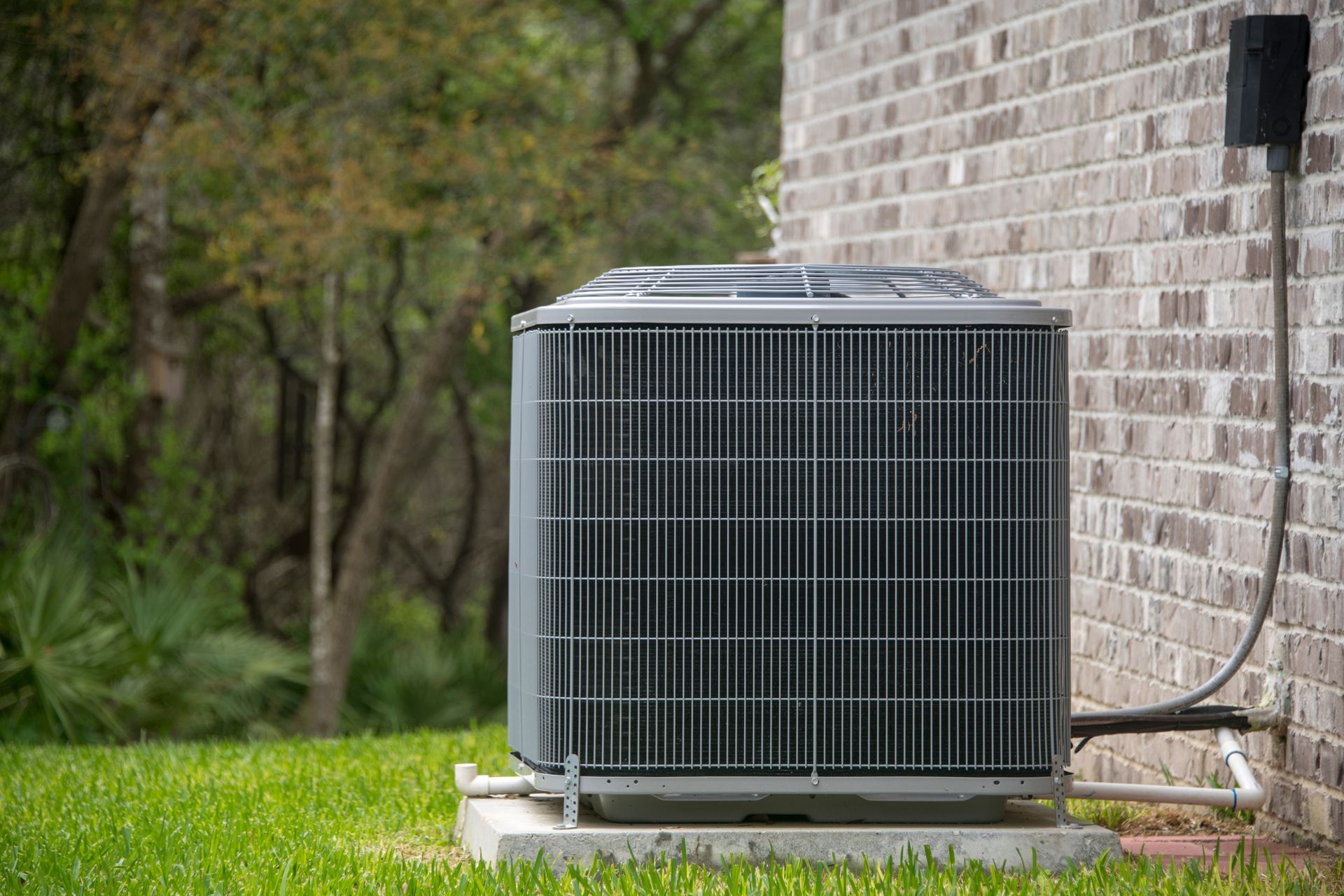 An air conditioner is sitting on the side of a brick building.