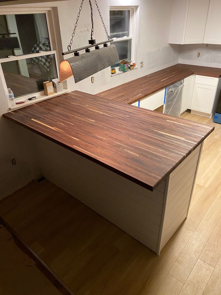 A kitchen with a wooden counter top and white cabinets.