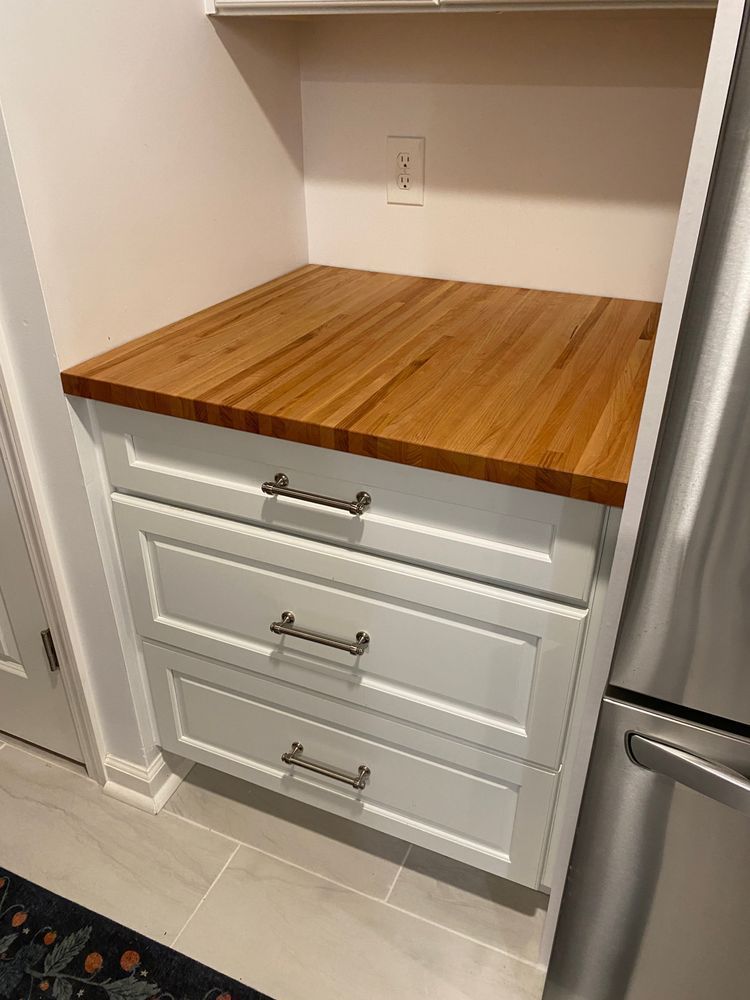 A kitchen with white cabinets and a wooden counter top.